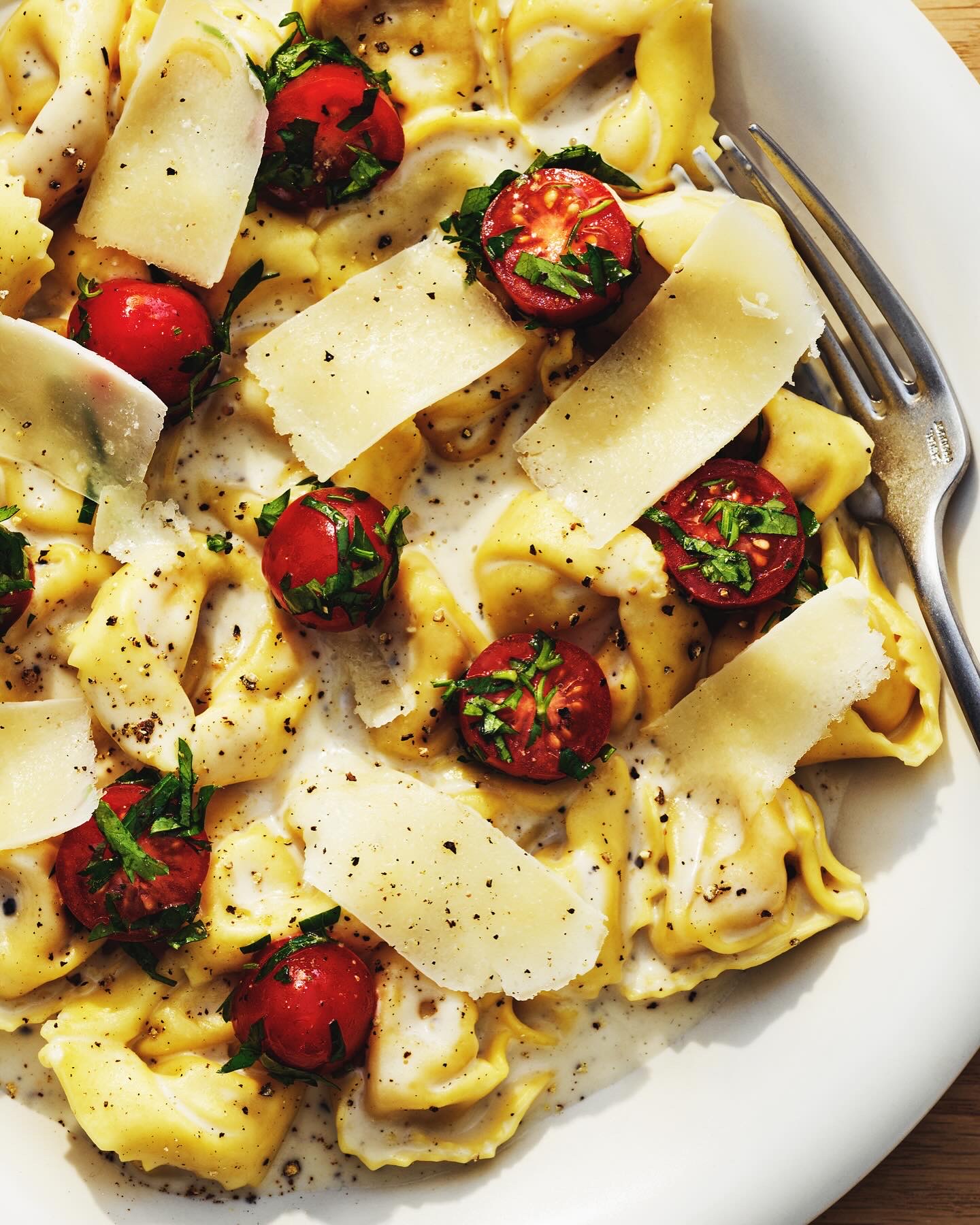 Tortellini in creamy cheese sauce with cherry tomatoes and parmesan crisps