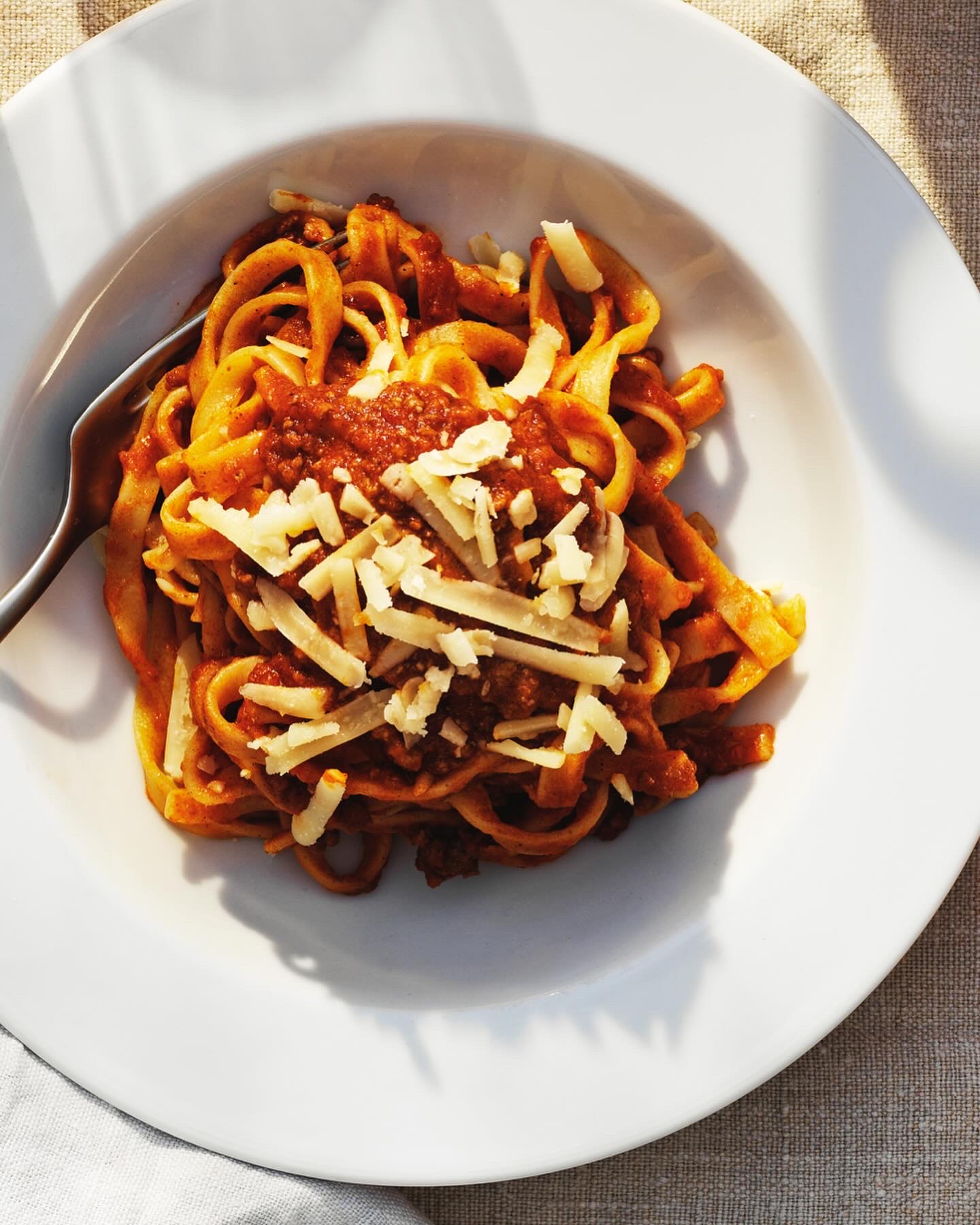 A plate of tagliatelle in rich meat sauce with grated cheese