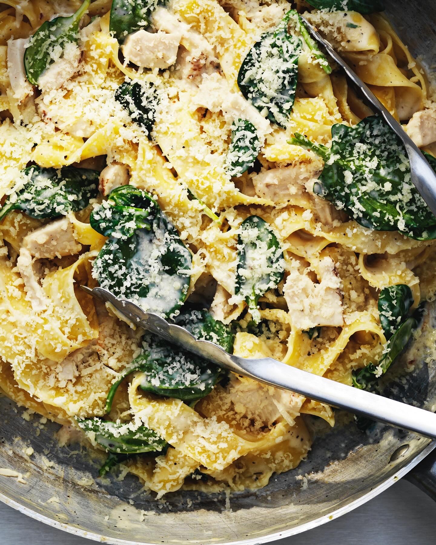 Creamy baked pasta with chicken, spinach and parmesan in a pan